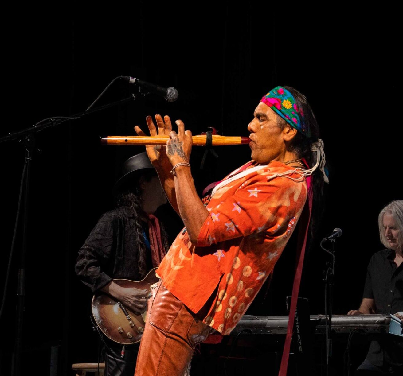 A man playing a flute on a stage.