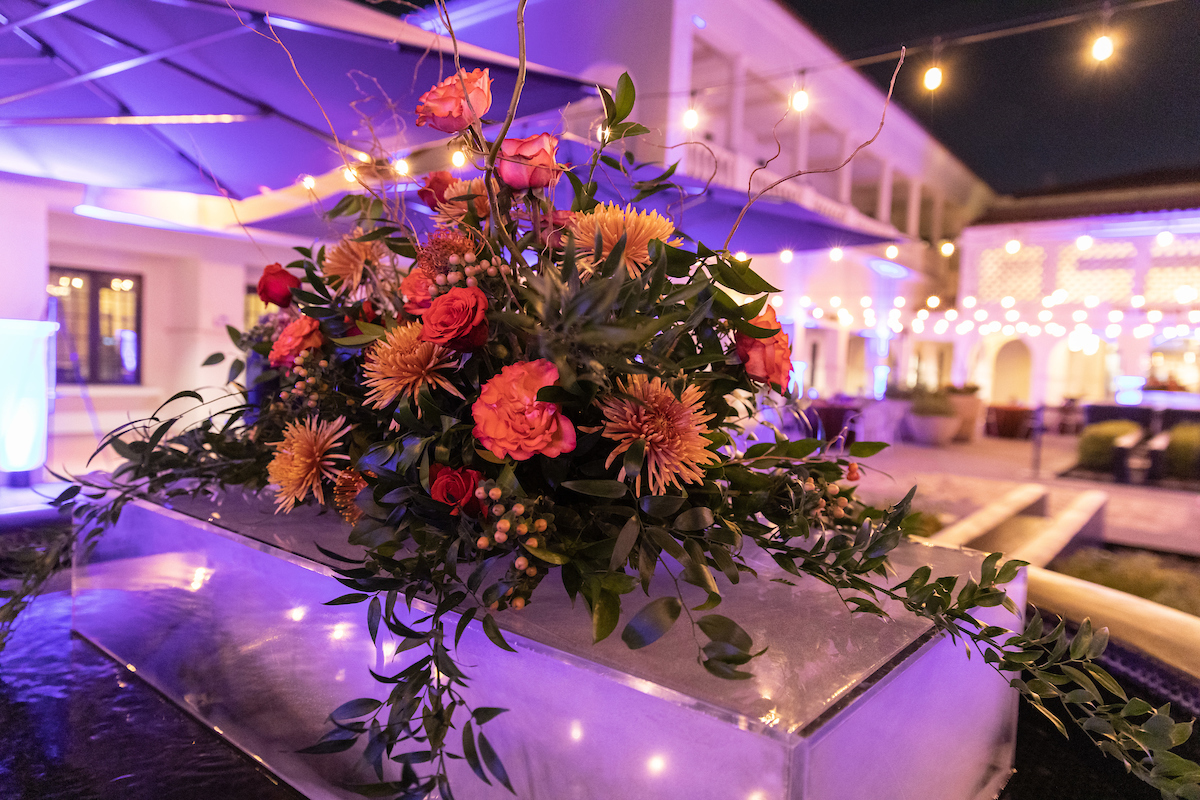 Floral centerpiece on display at an outdoor evening moondance event with string lights in the background.