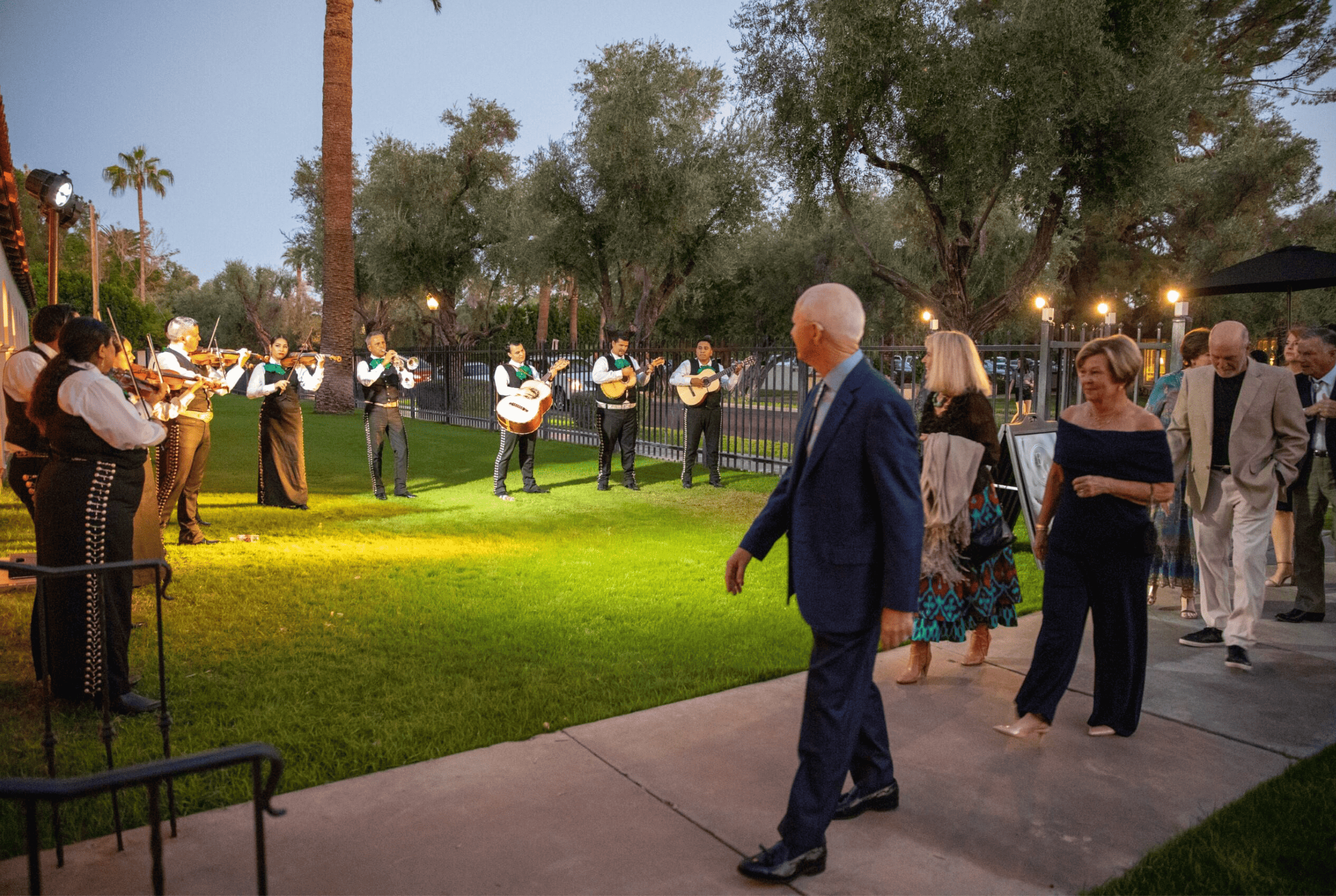 Guests arriving at an outdoor evening event with a mariachi band playing under a moondance.