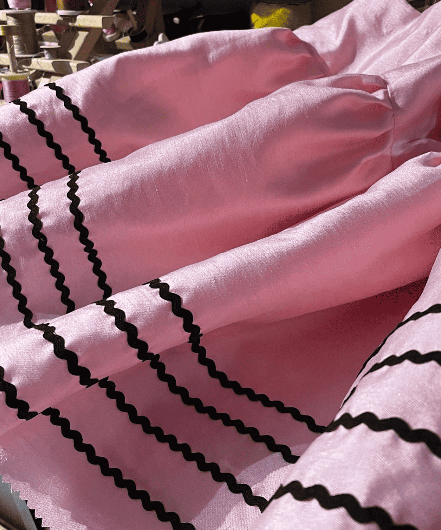 Pink fabric with black scalloped trim detail.