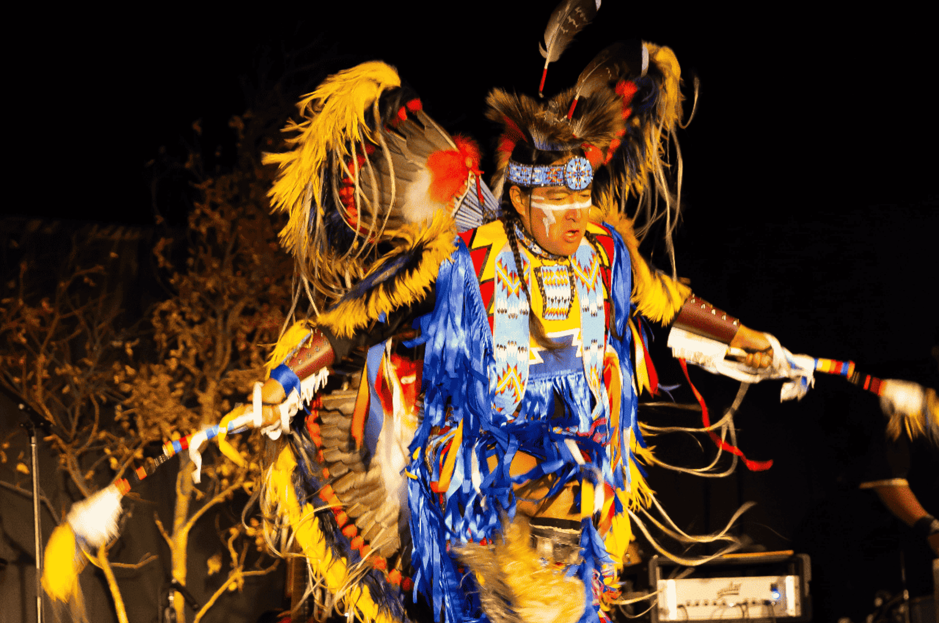 Indigenous person performing a traditional moondance in elaborately feathered costume.