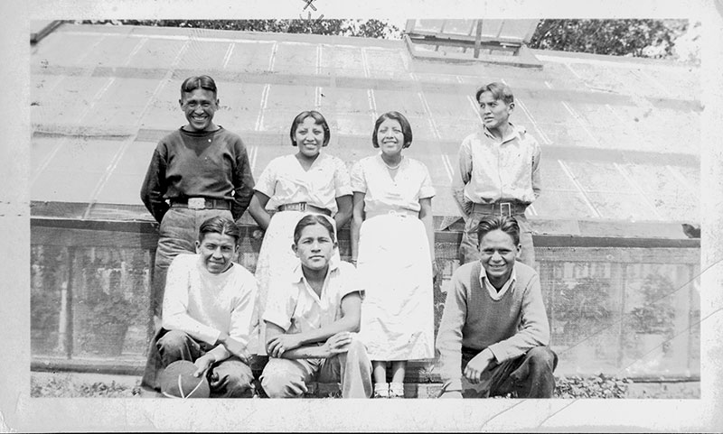 1930 black and white photo of Native youth in western period dress posing for the camera. One of the 2 young women in the photo is Pablita Velarde.