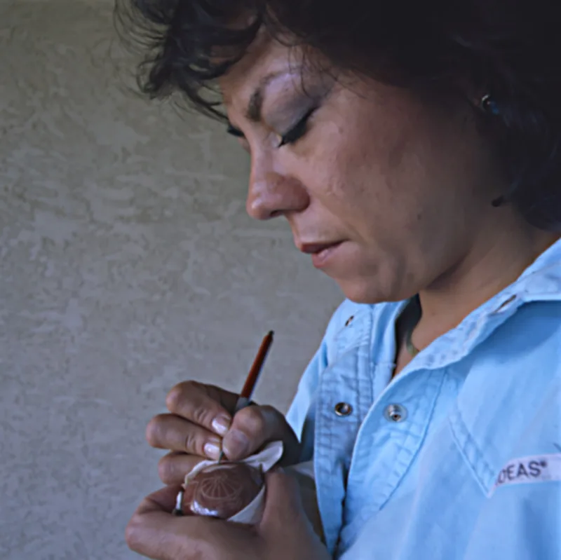 Rosemary Apple Blossom Lonewolf creating a design on one of her mini pottery vessels using the sgraffito technique