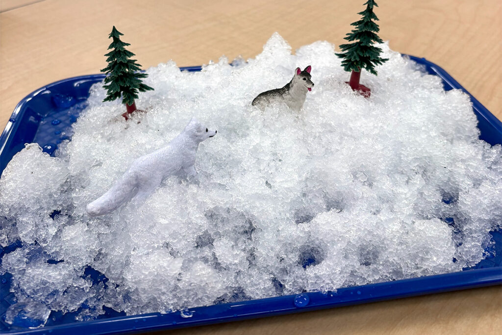 A tray filled with snow and toy figurines