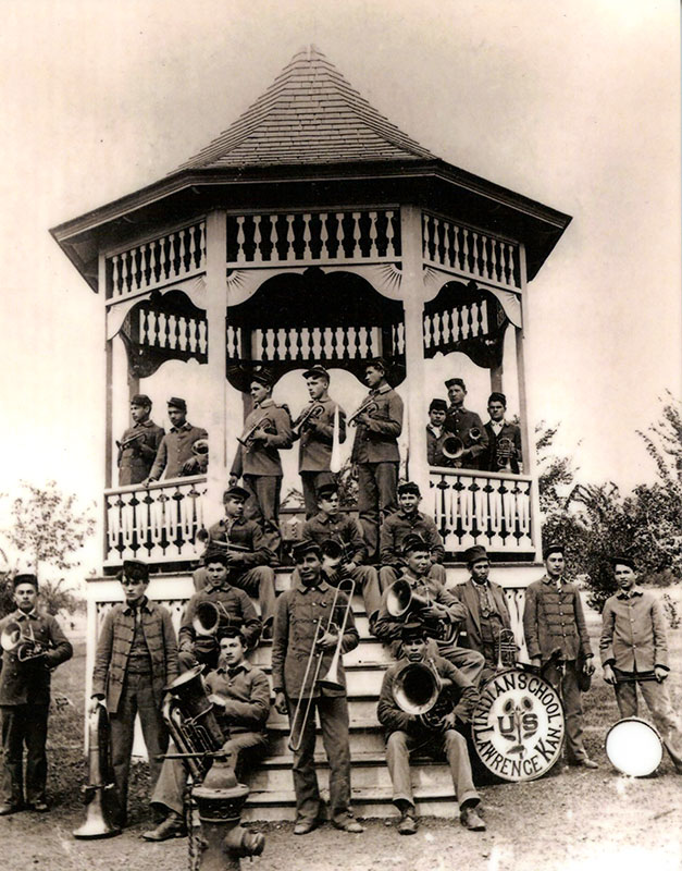 1904 black and white photo of all-male Native band posing with their instruments at a gazebo